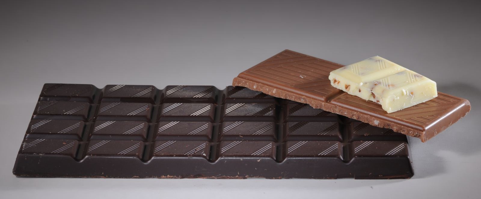 Bars of dark, milk and white chocolate stacked side by side
