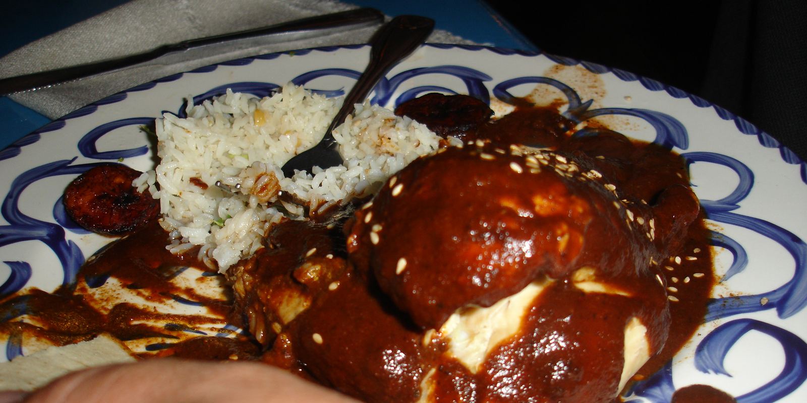 Chicken covered in dark mole poblano sauce with sesame seeds